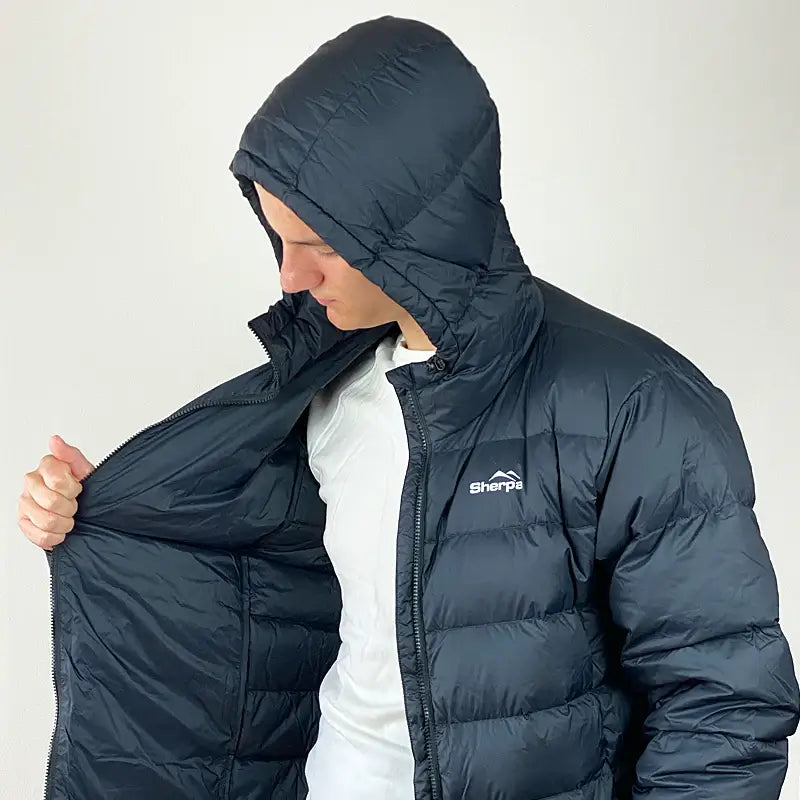 Load image into Gallery viewer, Man wearing Sherpa Men's Midweight 650+ Hooded Down Jacket, showcasing interior lining and compact hood. Great for warmth and comfort.