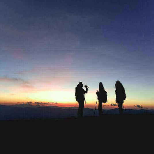 Hikers enjoying a drink at sunset, highlighting the beauty of outdoor adventures and the importance of eco-travel accessories. - Adventureco Blog