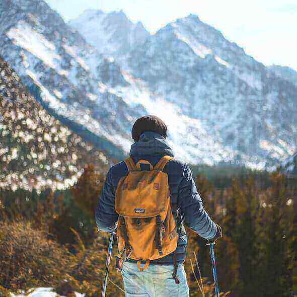 Person hiking with a backpack in snowy mountains, admiring the scenic view on a multi-day hiking adventure.