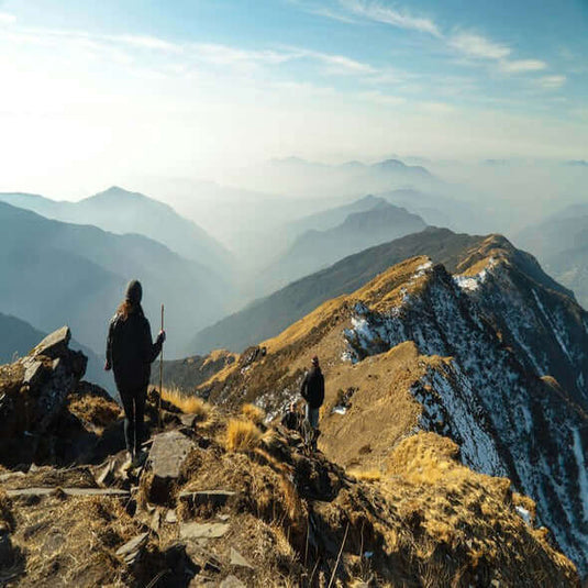 Hikers exploring a mountain trail with stunning panoramic views of layered hills and valleys. - Adventureco Blog