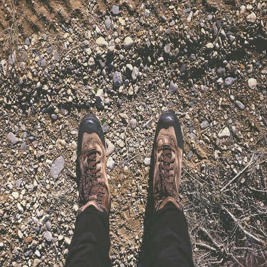 A pair of minimalist hiking boots on a rocky outdoor trail, highlighting their design for natural foot movement. - Adventureco Blog