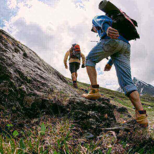 Hikers wearing appropriate boots climbing a rocky trail in the mountains