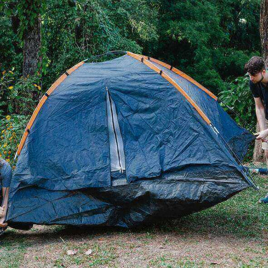 Securing a tent to ground with stakes and ropes to prevent it from blowing away in bad weather conditions