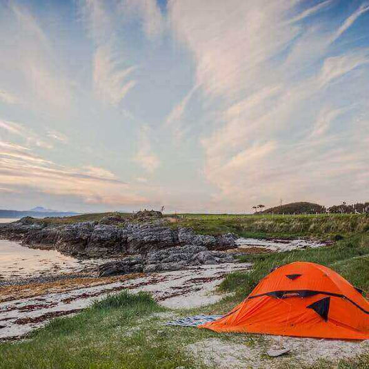 Zero-waste camping setup with orange tent by scenic Australian coastline at sunset - Adventureco Blog