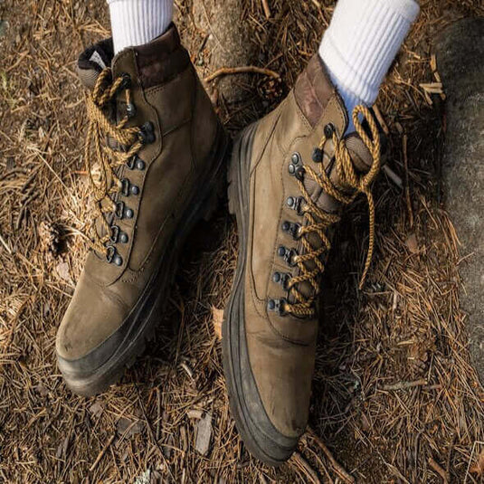 Close-up of sturdy hiking boots on natural ground, ideal for discussing barefoot shoe transition for hiking.