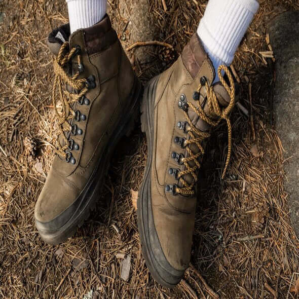Close-up of sturdy hiking boots on natural ground, ideal for discussing barefoot shoe transition for hiking.