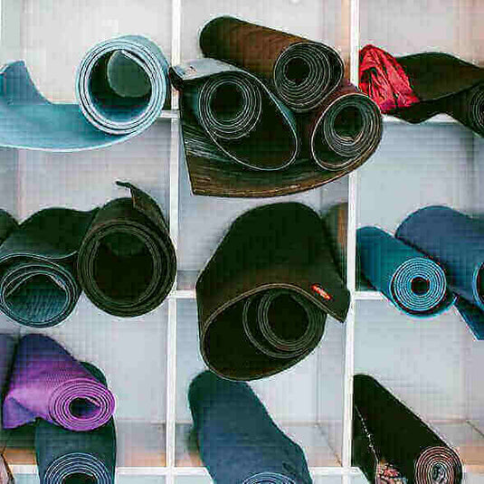 Rolled yoga mats in various colors stored in cubby shelves for outdoorsy and active lifestyle gifts