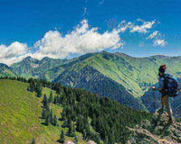 Hiker on a scenic mountain trail with a beautiful landscape of untouched nature and green hills in the background on a sunny day