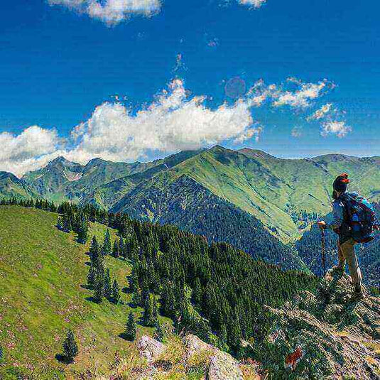 Hiker on a scenic mountain trail with a beautiful landscape of untouched nature and green hills in the background on a sunny day