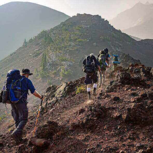 Hikers embracing eco-friendly practices on a mountain trail during a camping adventure - Adventureco Blog