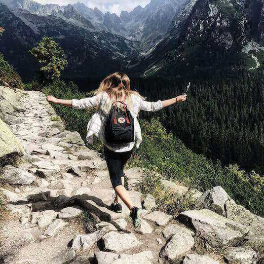 Person hiking on a rocky trail in a lush mountainous area, embracing the natural beauty of Australia's sustainable hiking destinations - Adventureco Blog