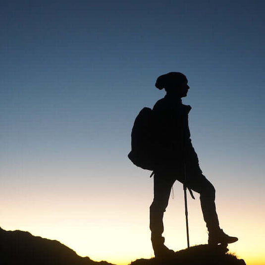 Silhouette of a hiker with a backpack walking stick against a dawn sky in Australia illustrating outdoor adventure. - Adventureco Blog
