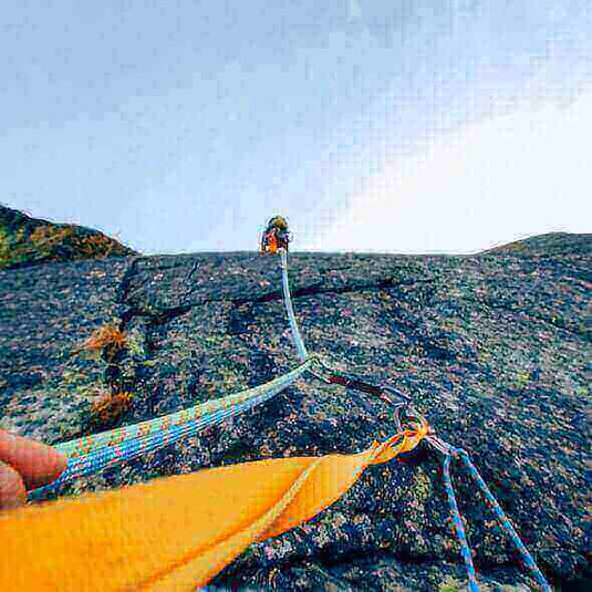 Climber scaling a rocky wall using safety ropes and carabiners, showcasing the importance of proper climbing gear for a safe adventure - Adventureco Blog
