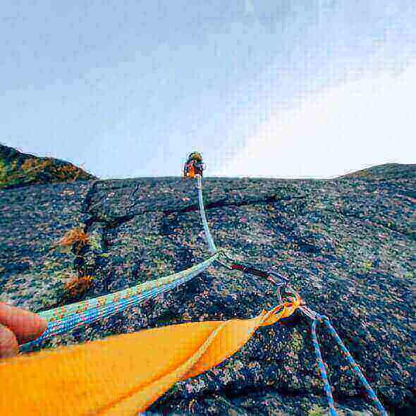 Climber scaling a rocky wall using safety ropes and carabiners, showcasing the importance of proper climbing gear for a safe adventure