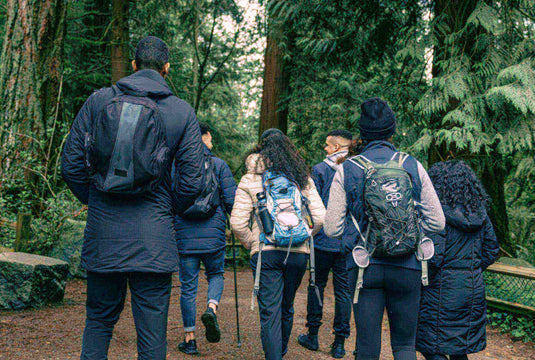 Group of hikers wearing backpacks walking on a forest trail