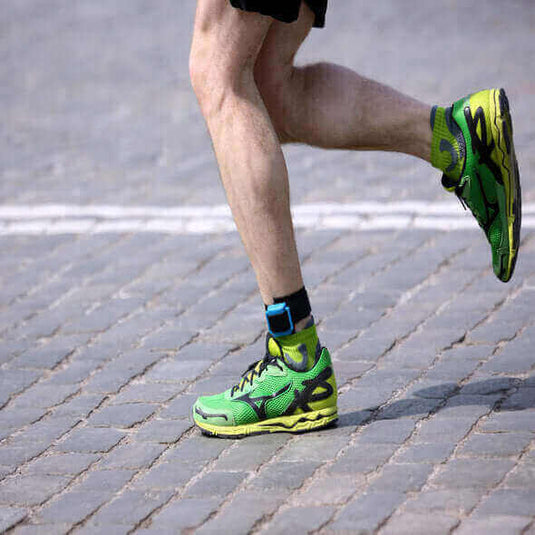 Runner wearing vibrant green and yellow barefoot shoes on a cobblestone path, showcasing natural movement. - Adventureco Blog