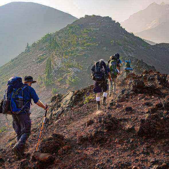 Hikers carrying backpacks hiking uphill on a rocky trail to avoid dehydration during outdoor activity