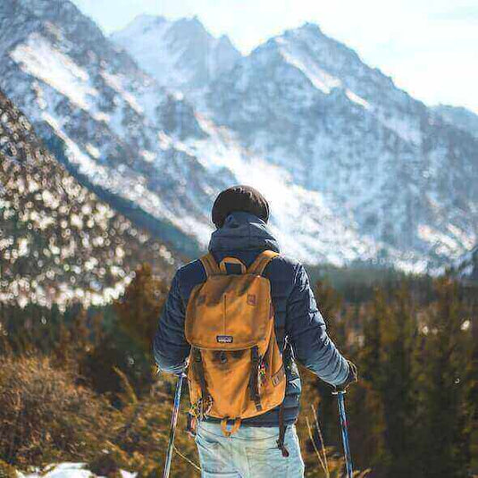 Hiker with yellow backpack enjoying breathtaking snowy mountain view in Australia - Adventureco Blog
