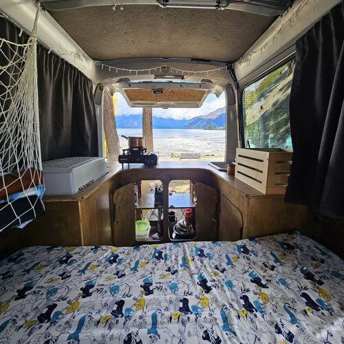 Cozy campervan interior overlooking scenic New Zealand landscape, ideal for road trips and outdoor adventures - Adventureco Blog