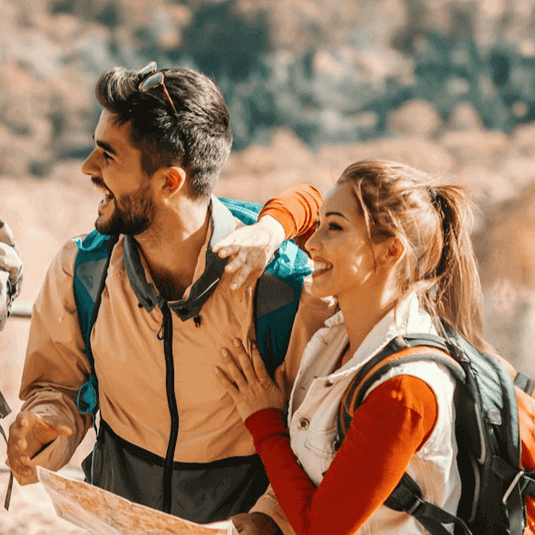 Happy couple wearing eco-friendly hiking gear in a sunlit outdoor setting - Adventureco Blog