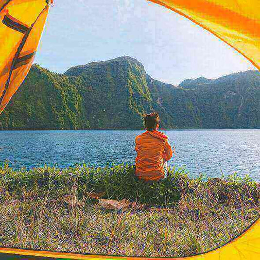 Camper enjoying a lake view from tent during a camping trip in nature