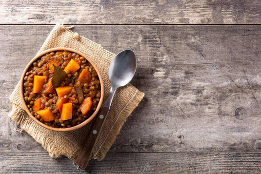 Hearty plant-based lentil stew with sweet potatoes and carrots in a bowl, perfect for eco-conscious camping adventures - Adventureco Blog