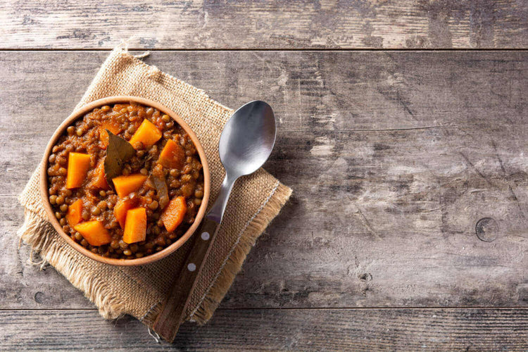 Hearty plant-based lentil stew with sweet potatoes and carrots in a bowl, perfect for eco-conscious camping adventures