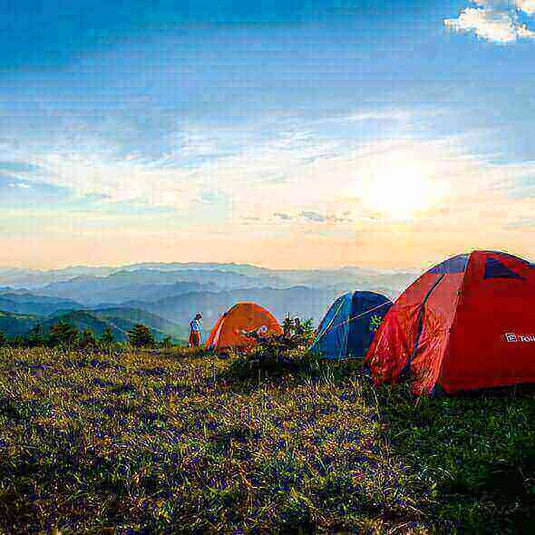 Tents set up at a scenic mountain campsite during sunset for an outdoor camping trip.