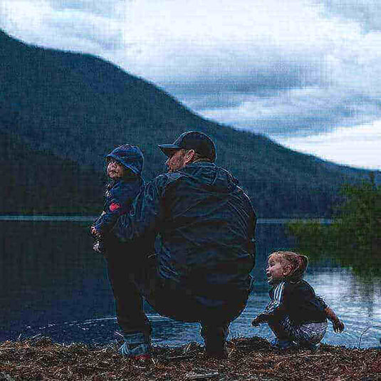 Father and toddlers enjoying an evening by the lake during a camping trip in the mountains.