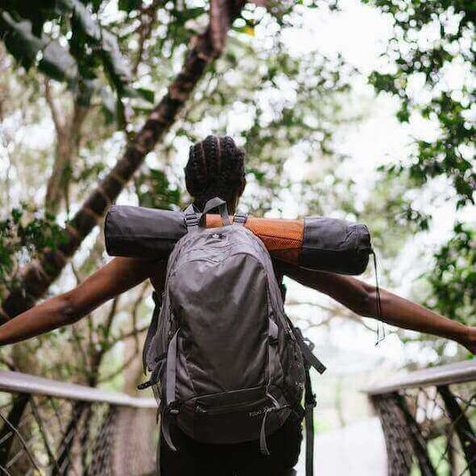 Person with backpack hiking through forest, practicing sustainable outdoor activities. - Adventureco Blog