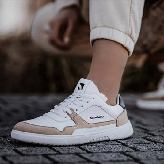 Person wearing stylish white and beige Barebarics barefoot sneakers with a flexible sole.