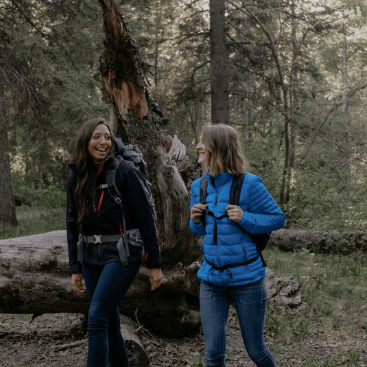 Women in fleece jackets enjoying a forest hike, showcasing stylish and functional outerwear for spring and winter outdoor activities.