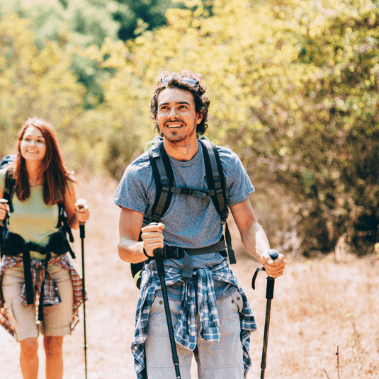 Man wearing performance shirt hiking with poles on a sunny day