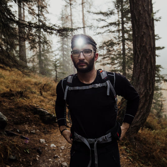 Outdoor adventurer using AdventureCo headlamp in forest at nightfall