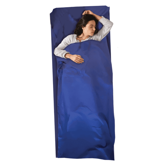 Woman sleeping in a blue Sherpa Cotton Sleeping Bag Liner for camping, hiking, and travel, providing cleanliness and comfort in warm conditions.