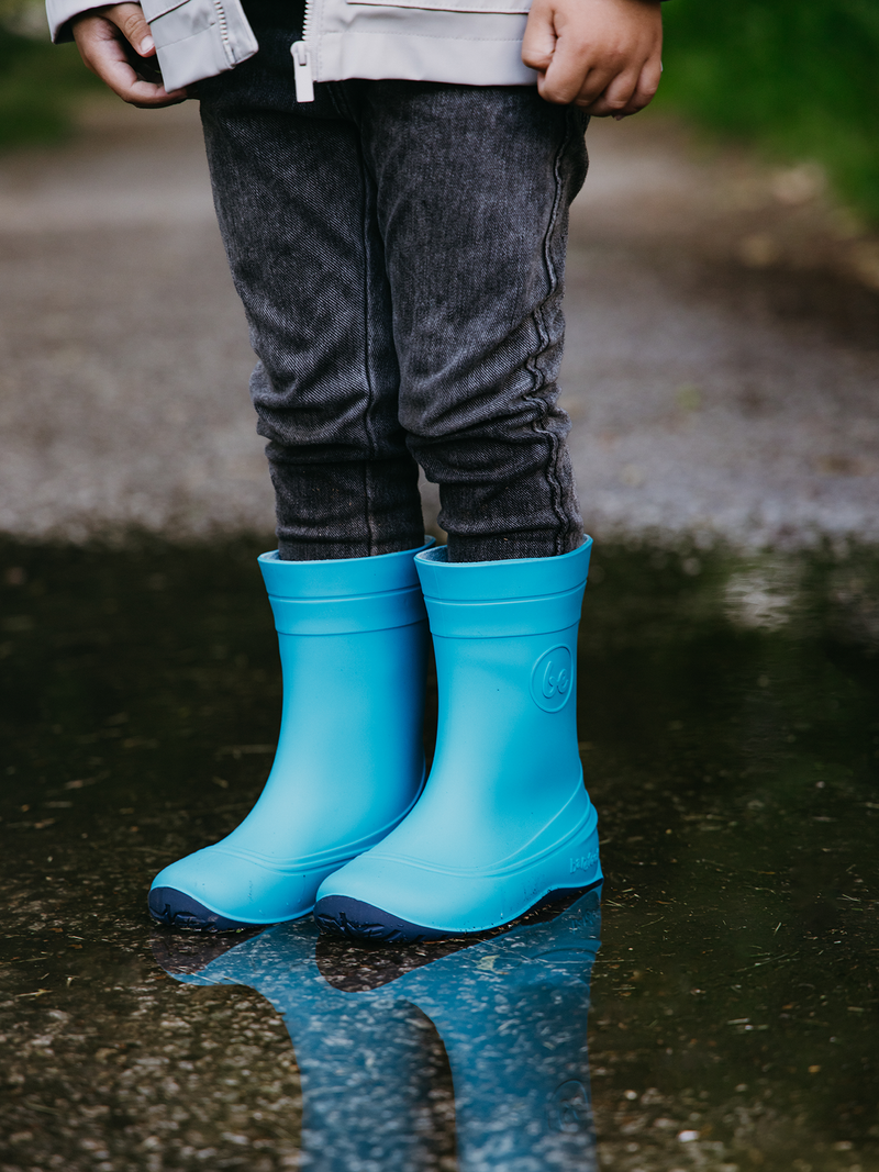 Load image into Gallery viewer, Child wearing Be Lenka Kids Barefoot Rain Boots in Aqua Blue, standing in a puddle outdoors.
