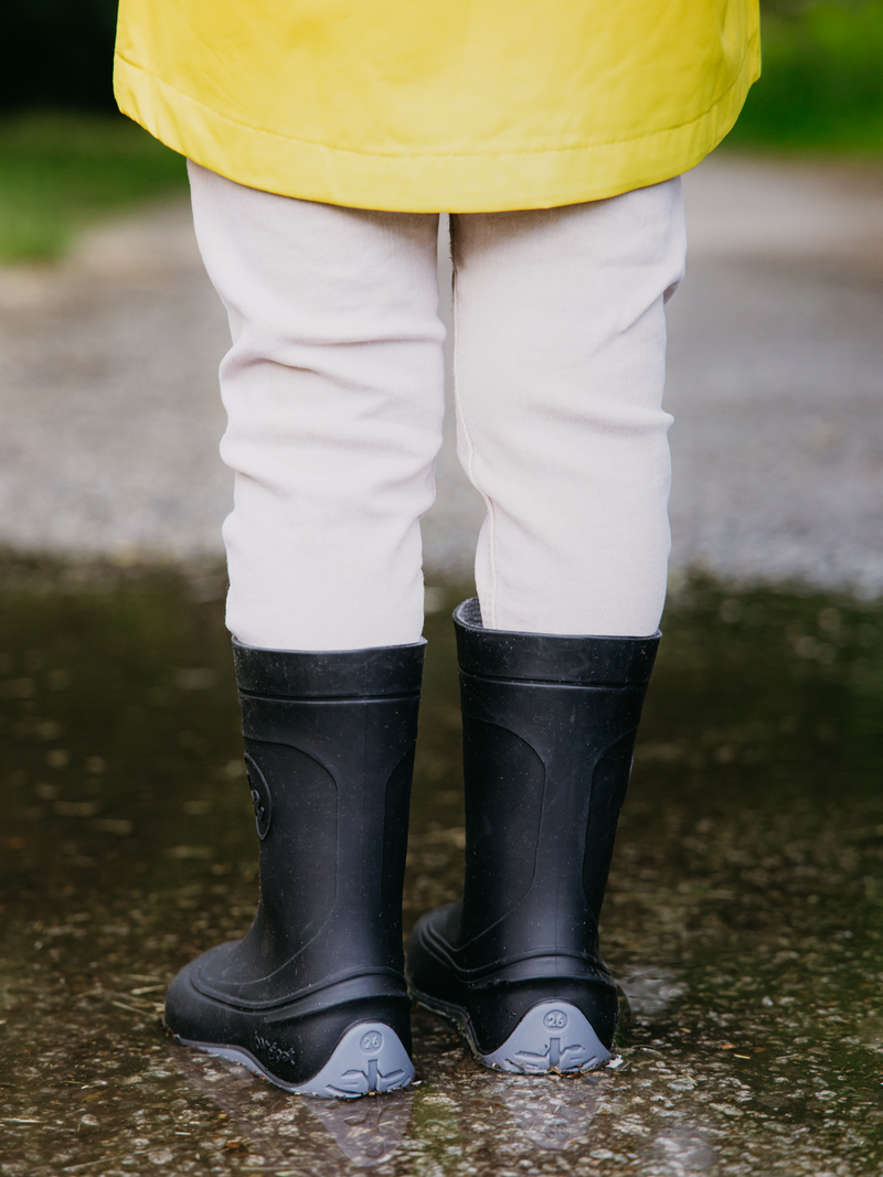 Load image into Gallery viewer, Child wearing Be Lenka Kids Barefoot Rain Boots in black, standing in a puddle, showcasing waterproof design.
