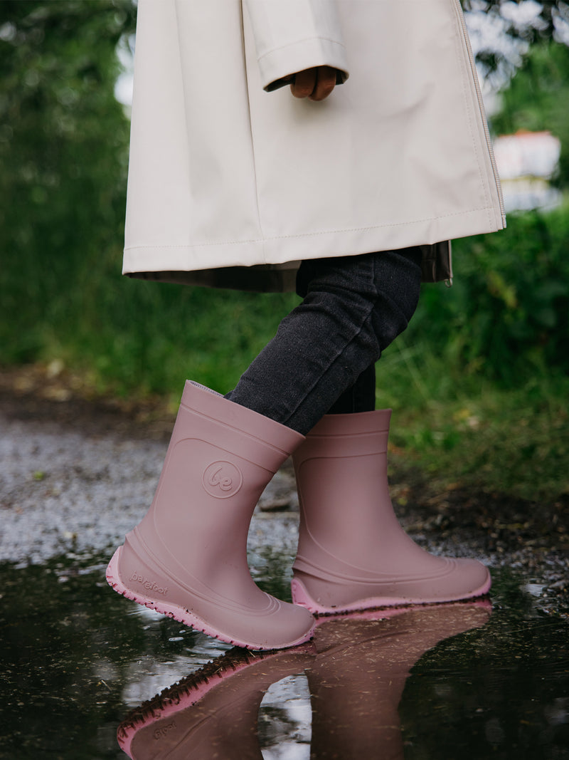 Load image into Gallery viewer, Child wearing Be Lenka Kids Barefoot Rain Boots in Misty Pink, walking through a puddle on a rainy day.
