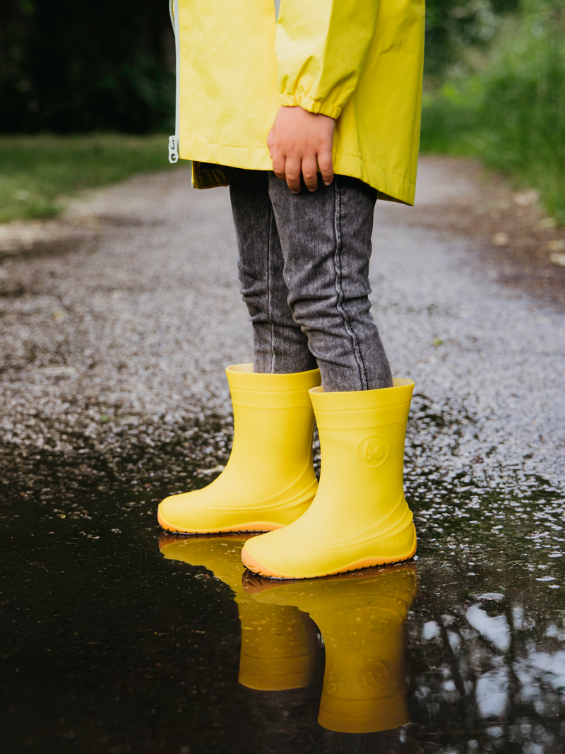 Load image into Gallery viewer, Child wearing Be Lenka Kids Barefoot Rain Boots in cheerful Yellow, standing in a puddle on a rainy day.
